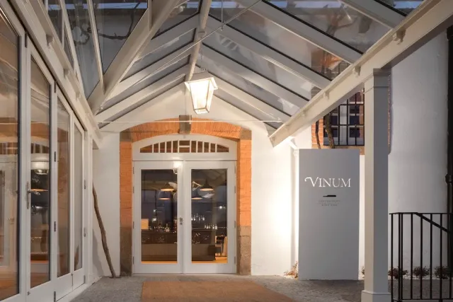 An entrance under a glass roof with white doors, a hanging lantern and a sign pillar