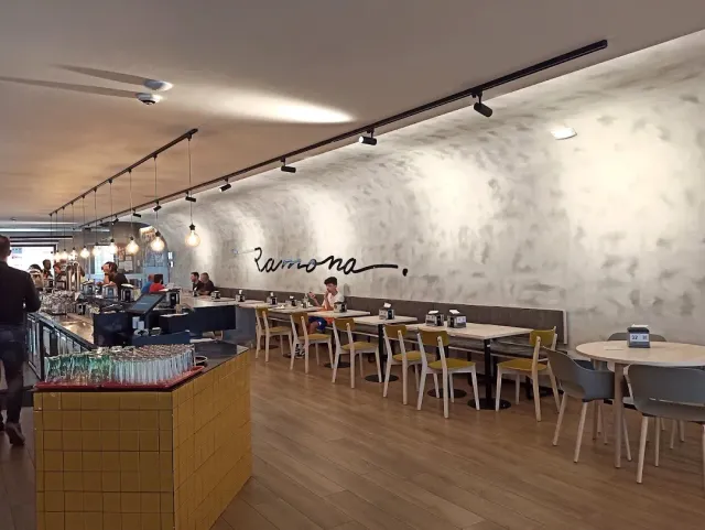 A modern room with a concrete wall, wooden floor, yellow chairs and a long counter