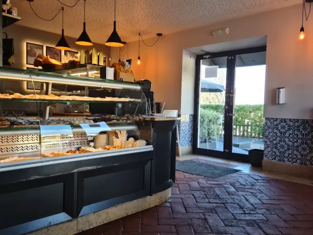 A long pastry display counter, hanging lamps and a red brick floor