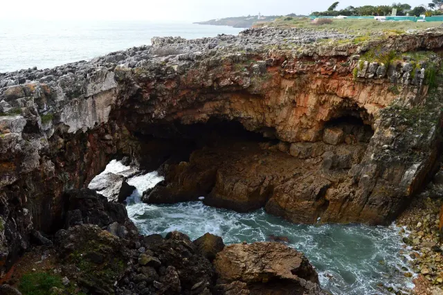 A hollow rock arch in the coastline with the sea crashing into it