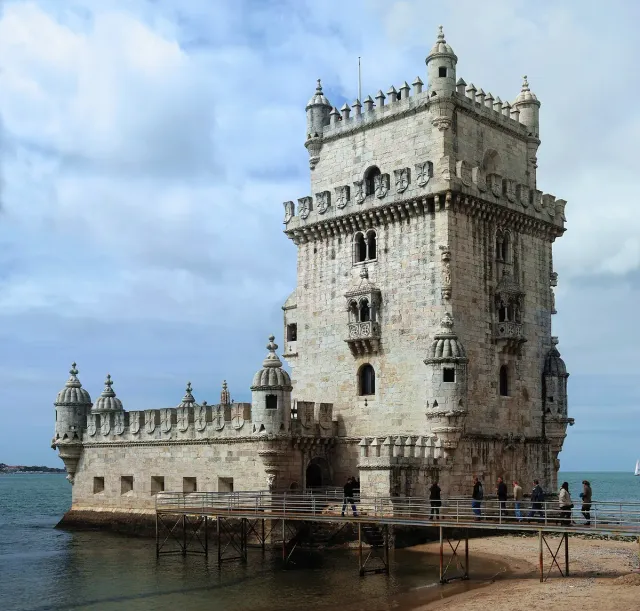 A fortified stone tower with carved balconies and turrets at the waterside