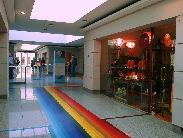 A small mall corridor with a striped colour floor and shop windows