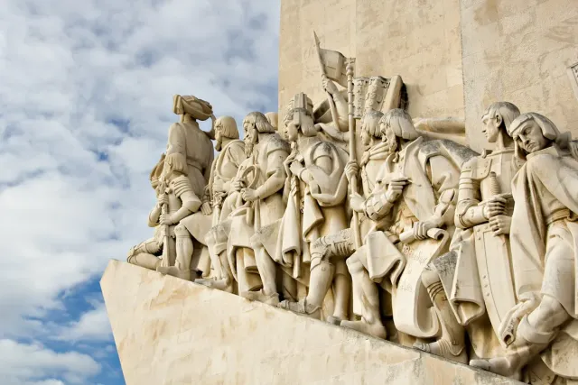 A row of carved stone figures in profile on the prow of a monument