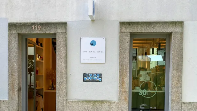 A granite facade with two doorways, a small sign, a tile plaque and a lit interior