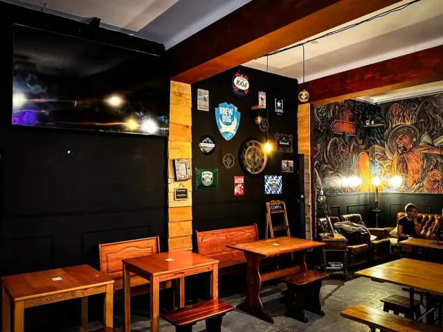 A pub with black walls, beer signs, wooden benches and a large mural