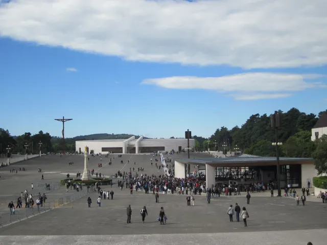 A vast esplanade with a crowd of worshippers before a modern basilica