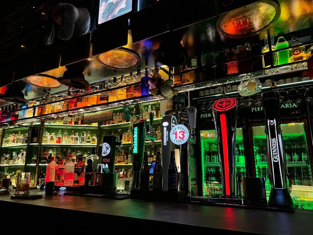 A bar counter with lit beer taps and colorful bottle shelves in neon light
