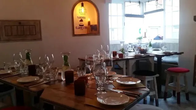 Wooden tables set with glasses, a lit niche in the wall and a bench by the window