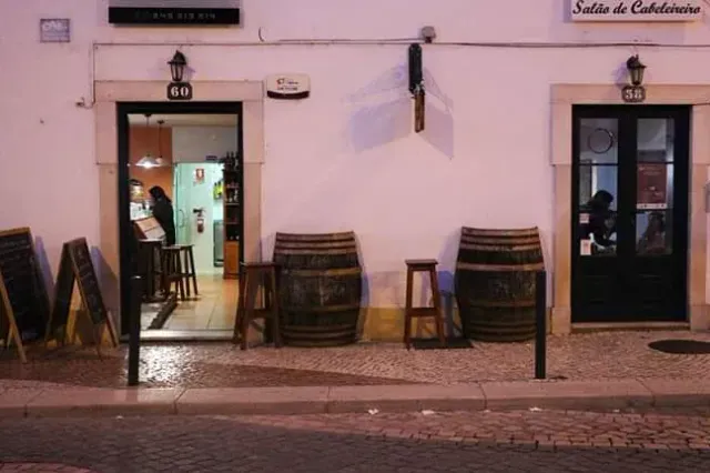 A street front at night with wine barrels as tables, chalkboards and a lit doorway