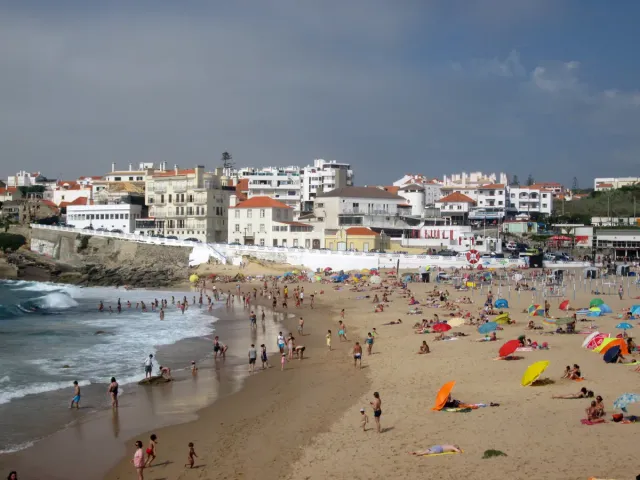 A village beach with bathers and parasols below a row of white houses