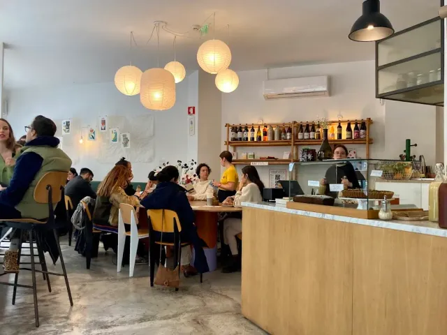 A bright space with round paper lanterns, a pale wooden counter and diners around tables