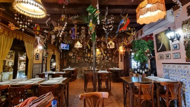 A hall crowded with hanging ornaments, colourful birds, azulejo tiles and rounded wooden chairs