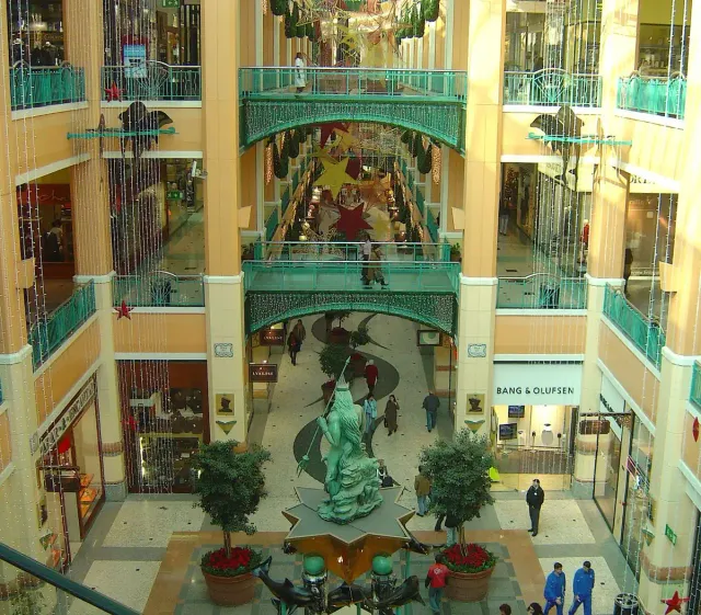 A multi storey mall atrium with decorated balconies and a statue at the centre