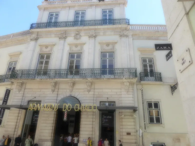 A pale neoclassical facade with iron balconies and gilded lettering above the entrance