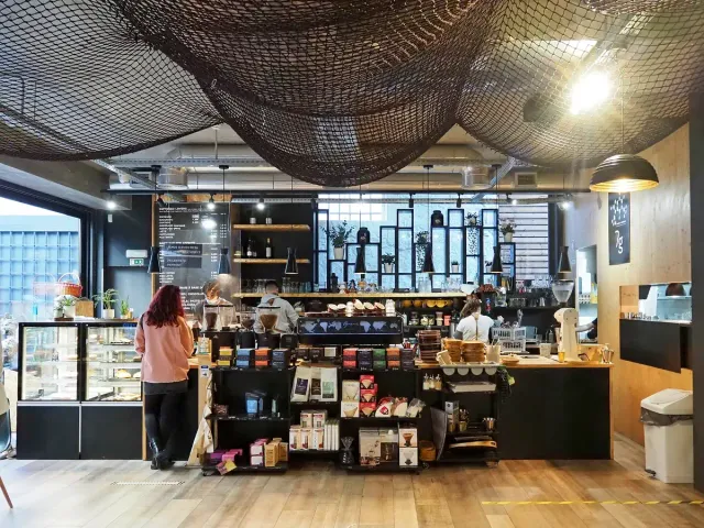 A roastery interior with a wooden counter, product shelves and hanging lamps