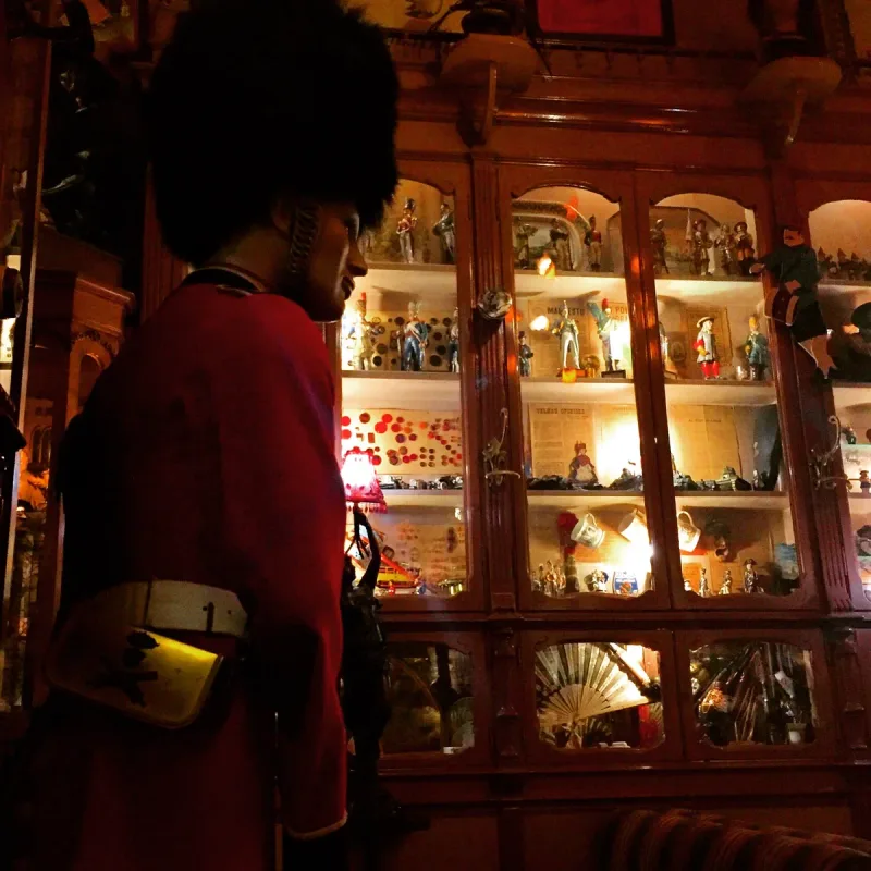 Wooden cabinets packed with thousands of collectibles beside a mannequin in a red uniform