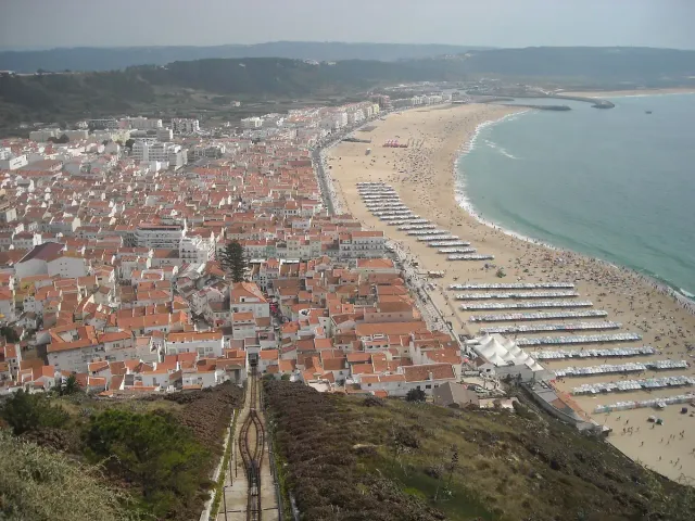 A steep funicular track dropping to a tiled town and a long bay beach