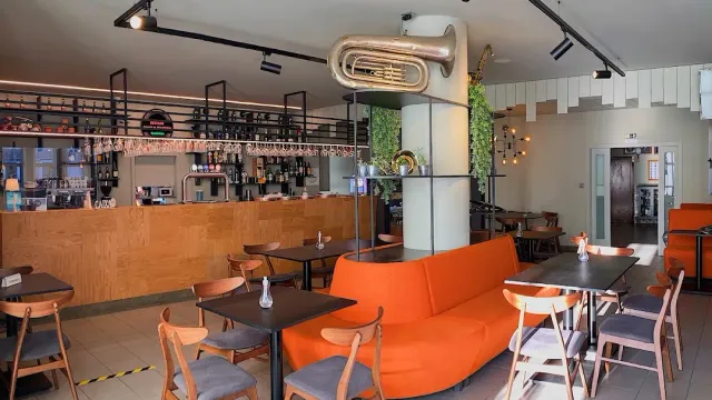 A space with an orange sofa, wind instruments hung on a column and a long bar counter