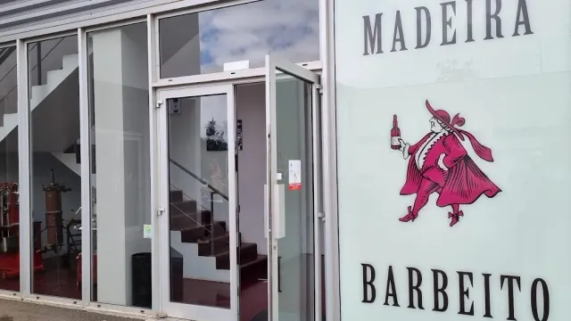 A glass entrance to a white building beside a drawing of a figure in pink holding a bottle