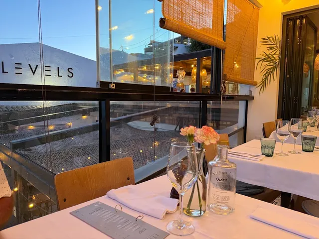 A set table with flowers by a glass window overlooking the rooftops at dusk