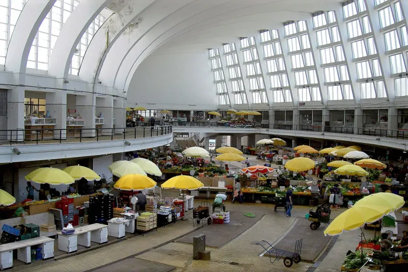 A bright vaulted hall with yellow parasols over produce stalls