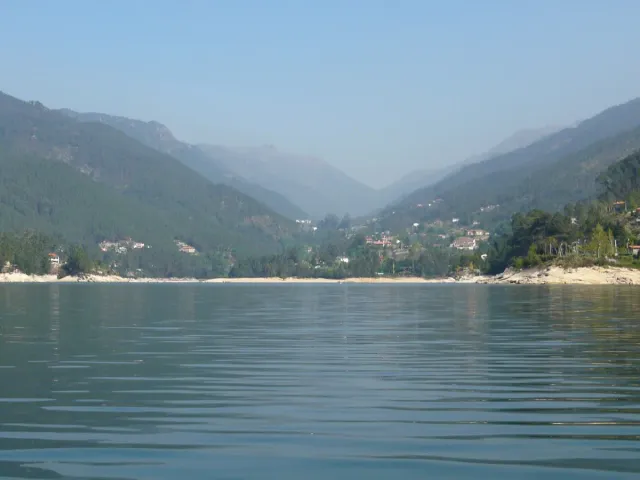 A wide reservoir between steep green mountain slopes
