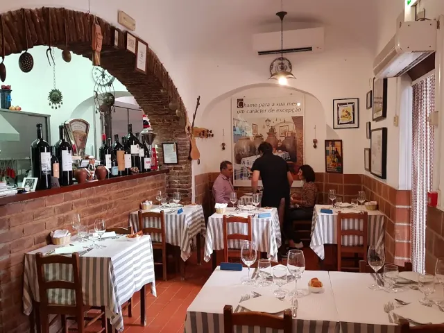A brick arch with wine bottles on the counter and tables in striped cloths