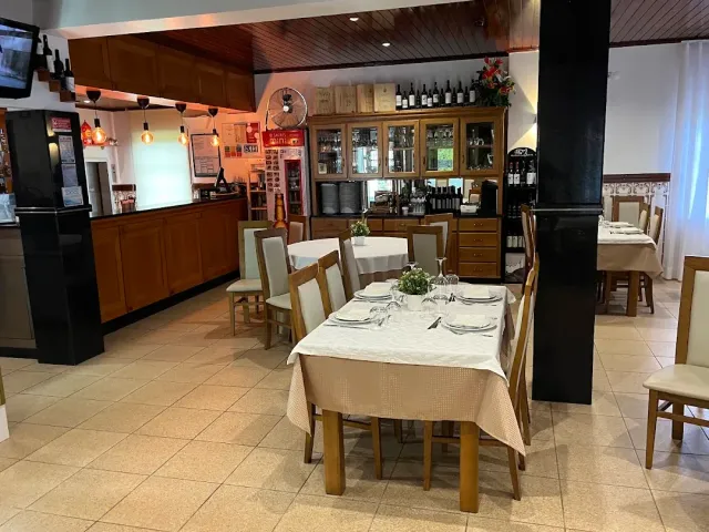 A hall with a tiled floor, a wooden counter, a bottle cabinet and tables set in pale cloths