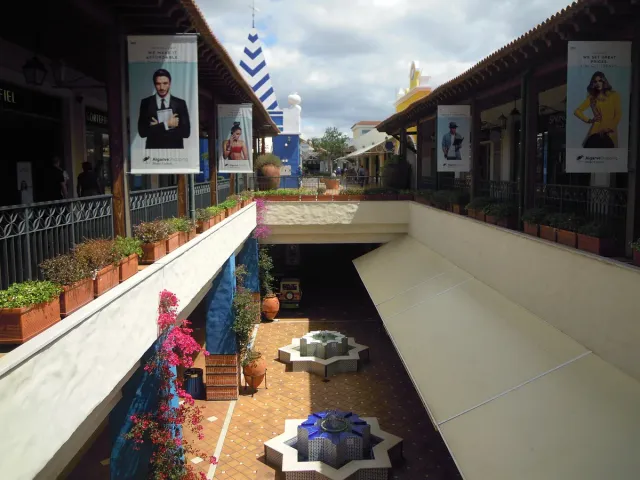 A covered mall walkway with shops on both sides and ceiling lighting