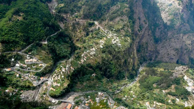 A small village on the floor of a deep valley between steep green rock slopes