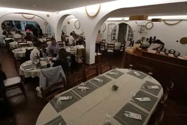 A room with white arches, an oval set table in front and diners in the background