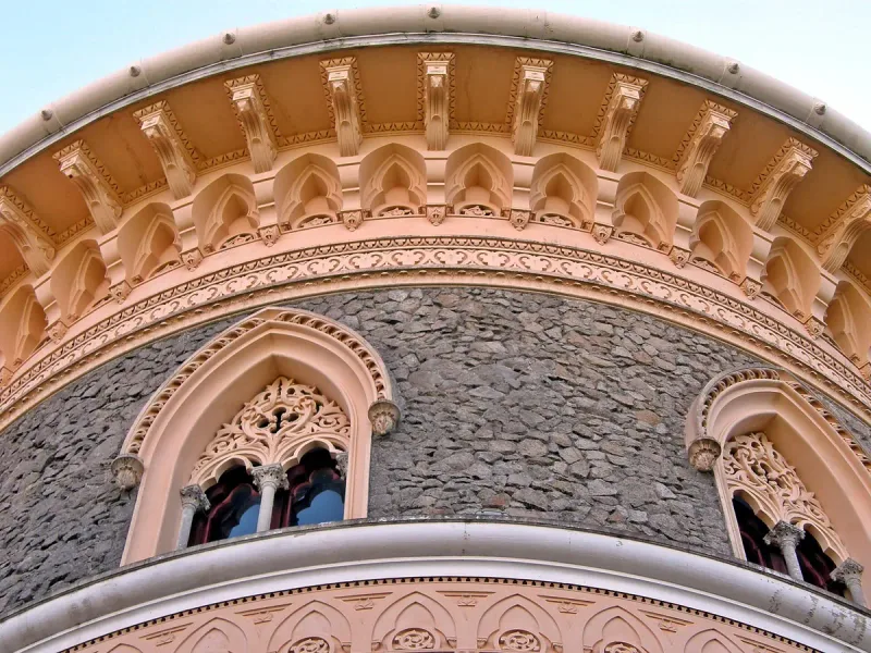A pink architectural detail of pointed arches and fine stone carving around paired windows
