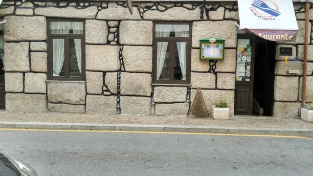 A granite stone facade with two windows, an entrance at the side and a white awning above it