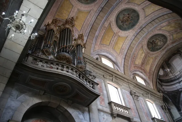 A baroque church interior with a gilded organ, vaults and a painted dome