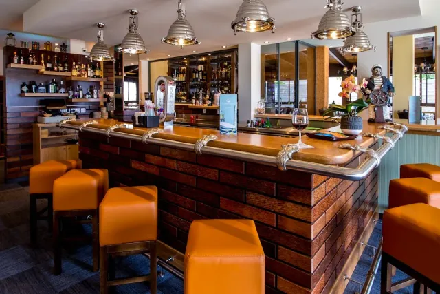 A bar with a brick base, orange stools, metal lamps and a sailor figurine