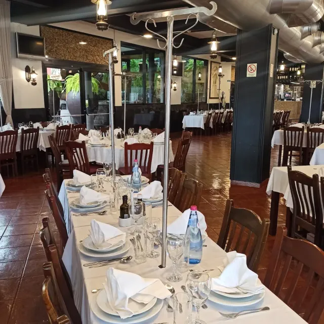 A large room with white tablecloths and a tall skewer stand on the table