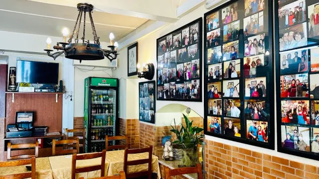 Walls covered in framed photographs of guests, an iron chandelier and a drinks fridge