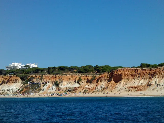 Tall red and gold cliffs above a narrow strip of sand