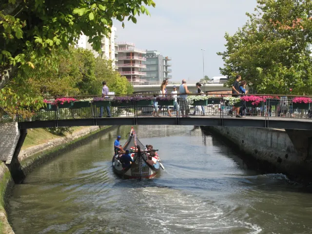 A colourful boat with passengers in a narrow canal between town houses