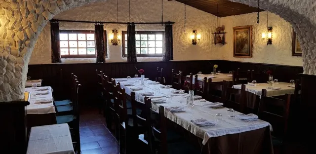 A vaulted room with stone walls, long tables in white cloths and wall lamps