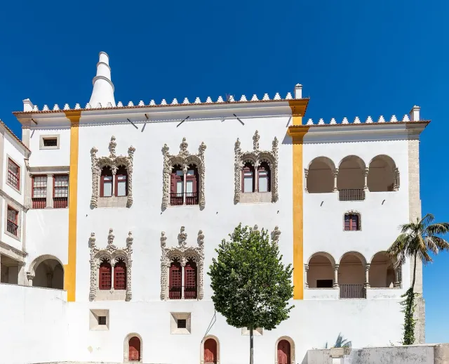 A white palace with carved windows and two huge conical chimneys