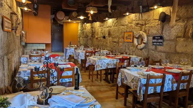 A stone room with patterned tablecloths, a life ring on the wall and copper pots