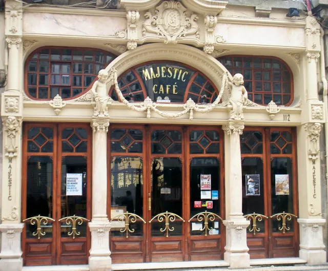 A carved art nouveau front with tall arched windows and a gilded sign