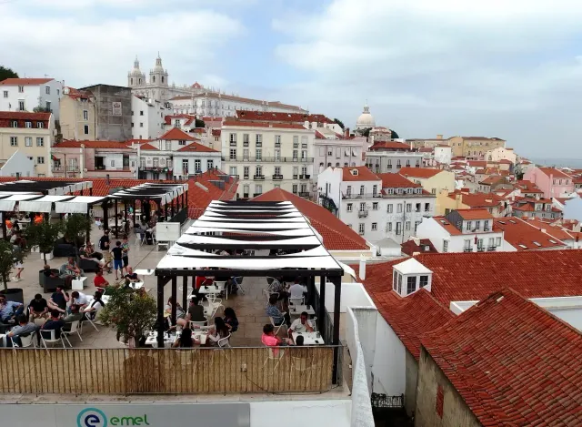 A terrace with striped awnings above dense tiled roofs and a wide river