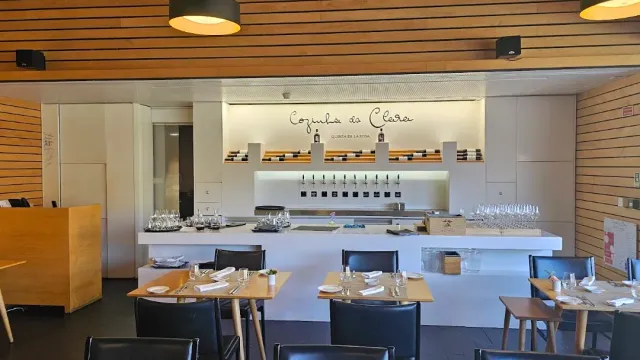 A modern room with a wooden ceiling, an open kitchen counter and set tables