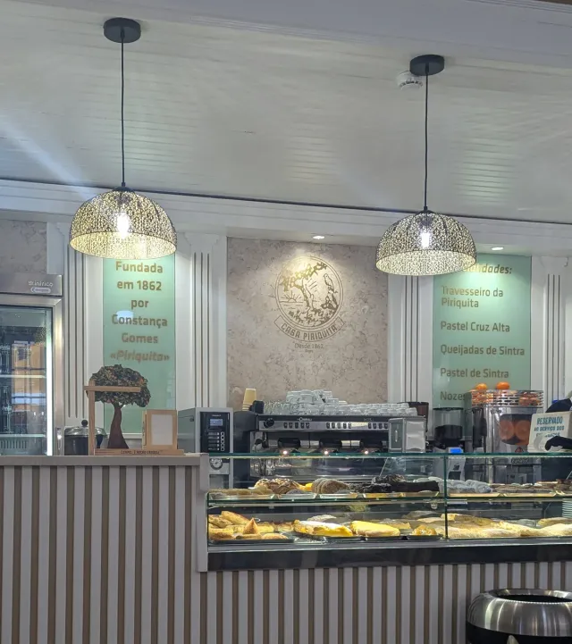 A bakery interior with a glass counter, hanging lamps and a product board