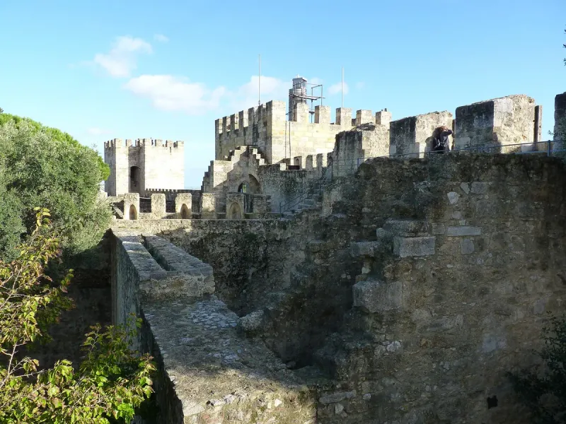 Crenellated stone walls and towers above a moat against a blue sky