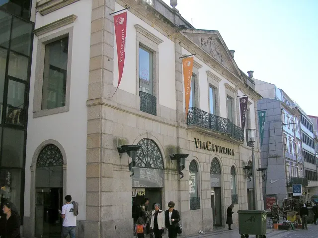 A rendered classical front with banners and a sign above a pedestrian street