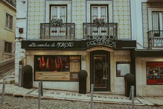 A facade tiled with ceramic tiles, iron balconies and a display window of cured meat
