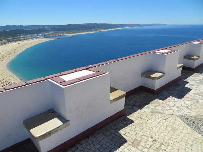 A whitewashed viewing terrace above a long sandy bay and blue sea